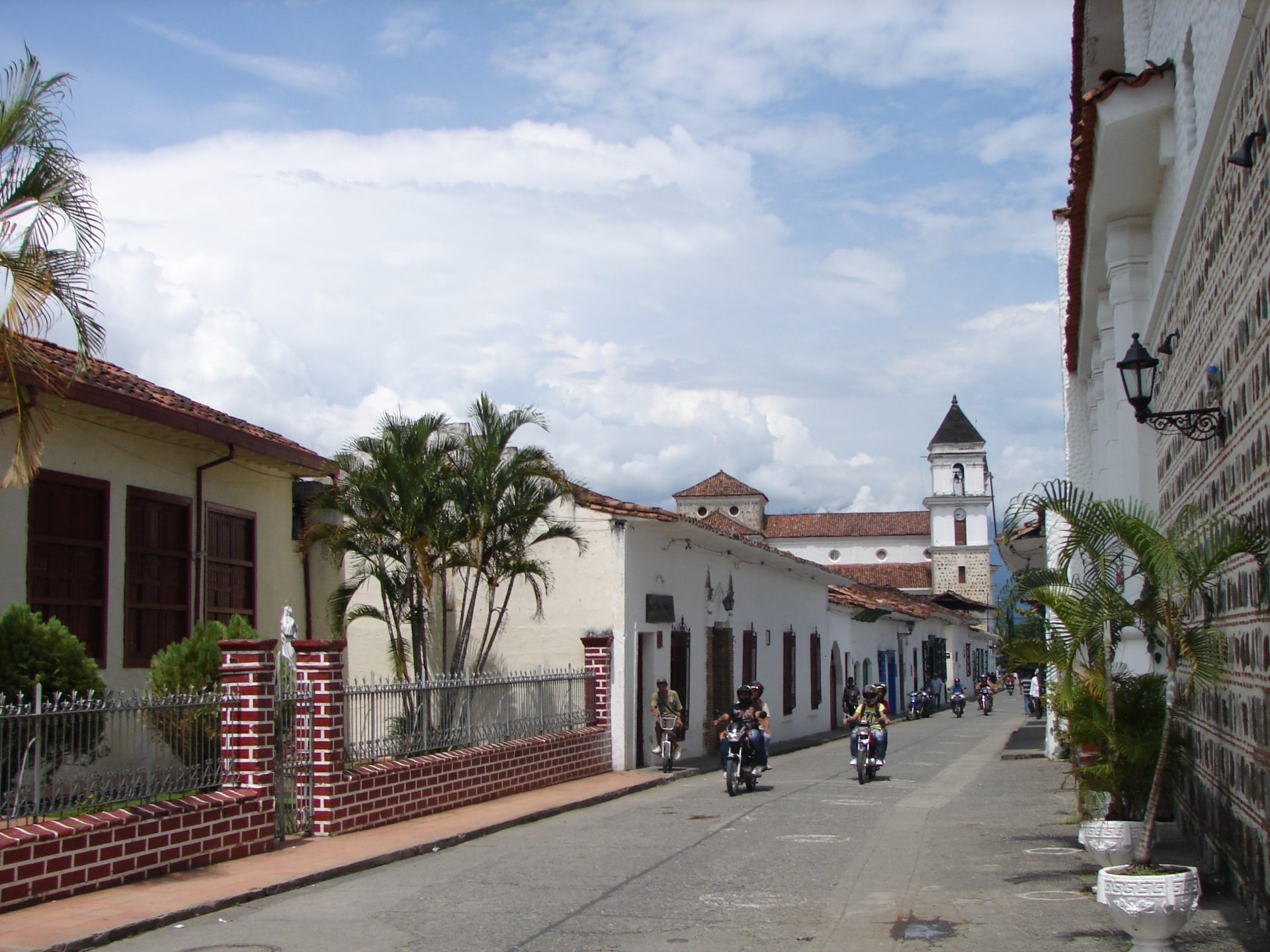 Calle colonial de Santa Fe de Antioquia con palmeras y la torre de la iglesia