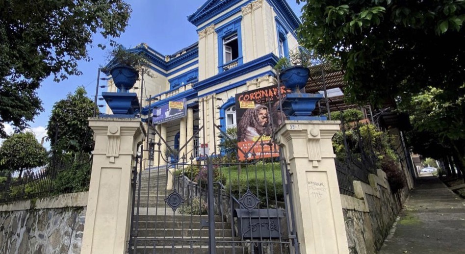 Heritage mansion with a blue and cream façade, stone steps and iron gate in Medellín's Prado neighbourhood