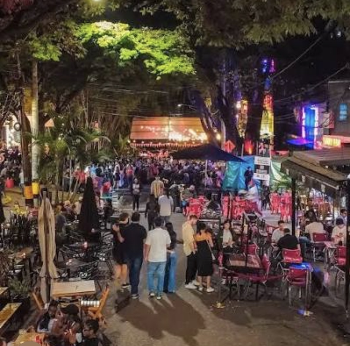 Een straat in Provenza vol mensen 's avonds, met verlichte bars en terrassen aan beide kanten